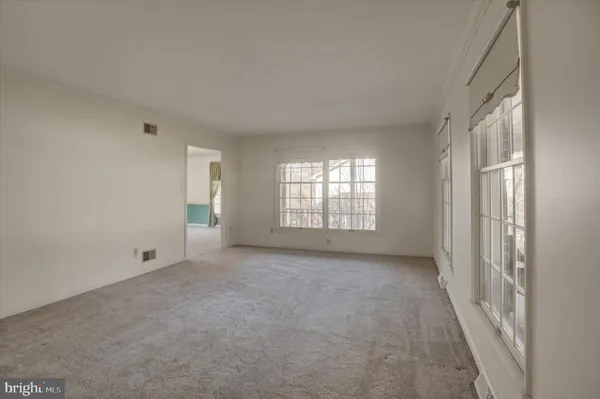 an empty room with wooden floor fireplace and windows