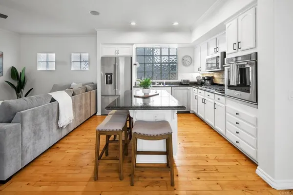 a large kitchen with kitchen island a large window and stainless steel appliances