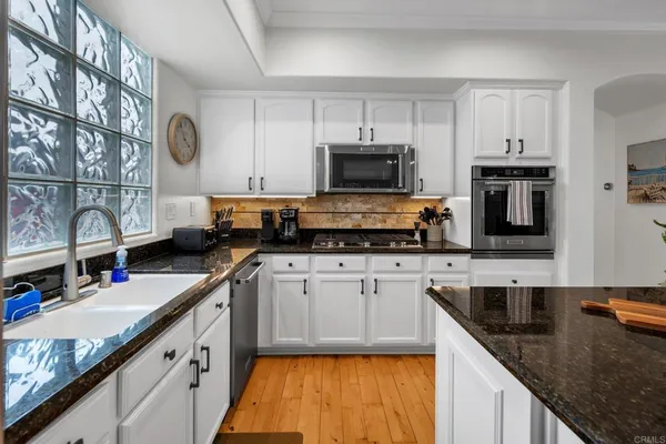 a kitchen with stainless steel appliances granite countertop a sink a stove and cabinets