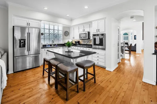 a kitchen with stainless steel appliances a dining table chairs refrigerator and microwave