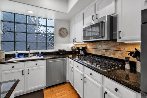 a kitchen with stainless steel appliances granite countertop a stove a sink and a microwave