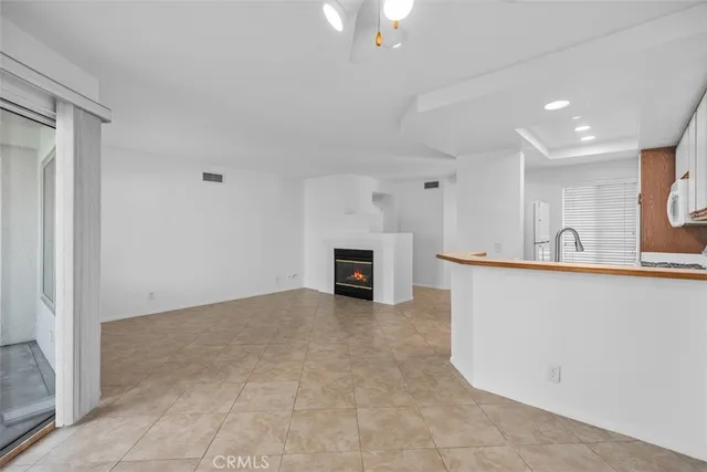a view of kitchen and empty room with fireplace
