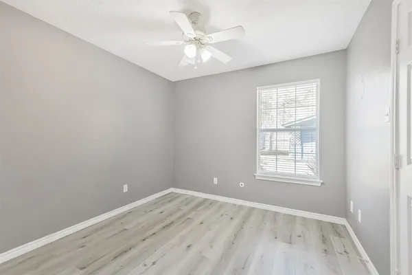 an empty room with a window and a ceiling fan