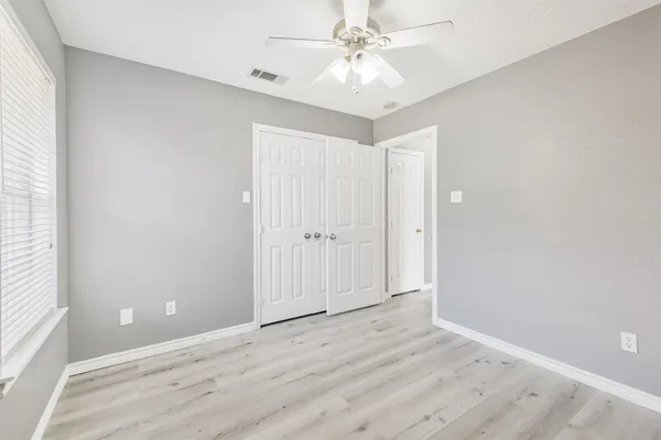 an empty room with wooden floor and ceiling fan