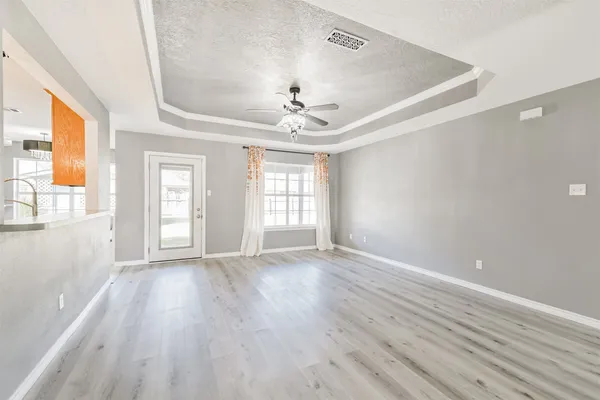 a view of an empty room with a window and wooden floor