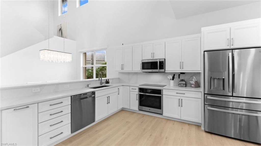 6172 Dogleg Drive Naples, FL 34113 - Photo 24 of 45 a kitchen with white cabinets and stainless steel appliances