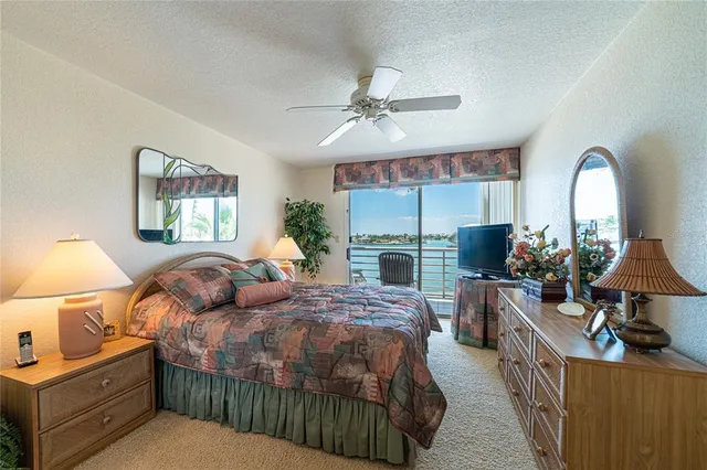 a bedroom with bed a chandelier and a large window