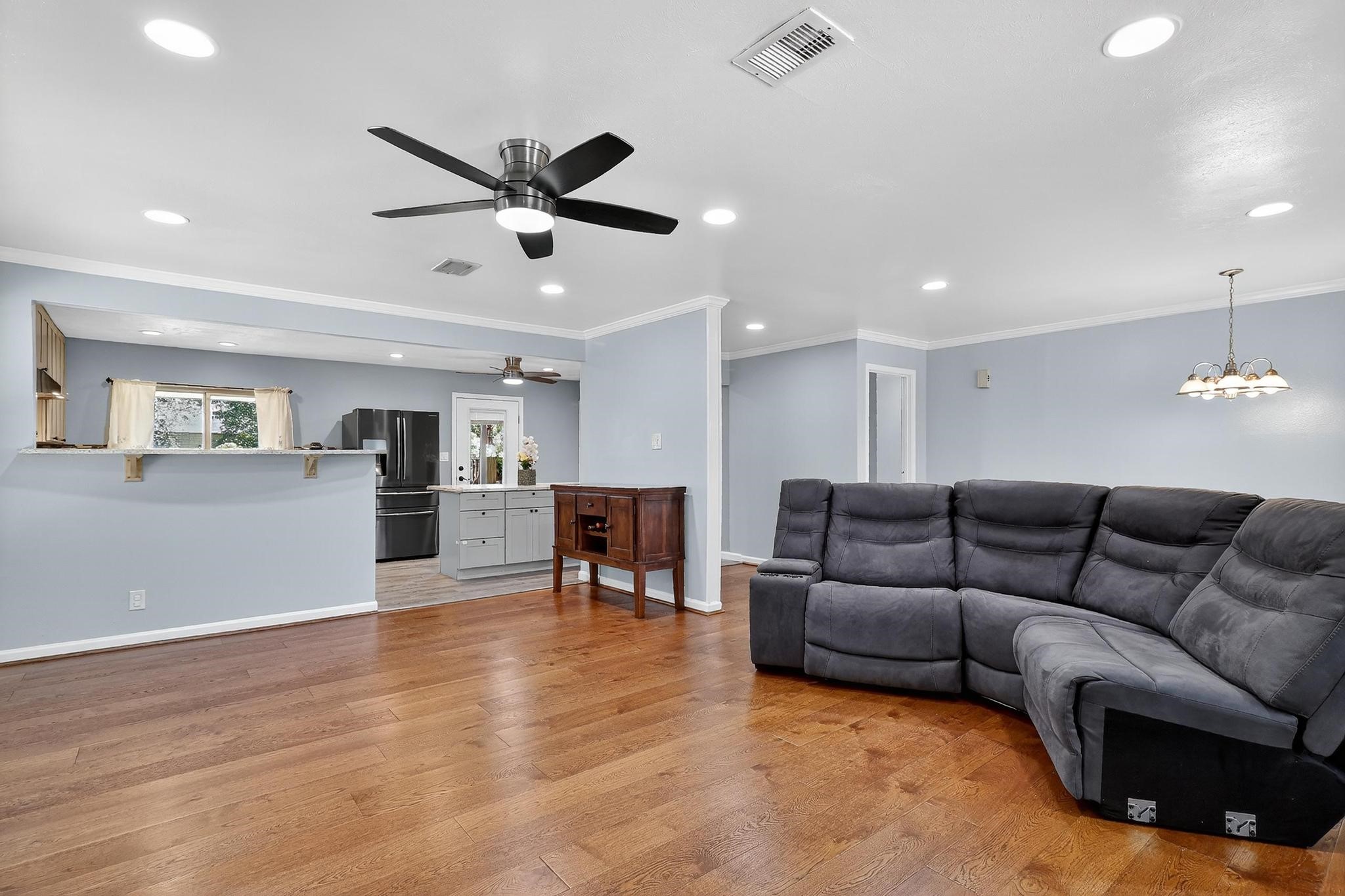 14418 Louetta Road Cypress, TX 77429 - Photo 15 of 39 Open-concept living area with hardwood floors, recessed lighting, and a modern ceiling fan, offering a bright, comfortable space that flows seamlessly into the kitchen and dining areas.