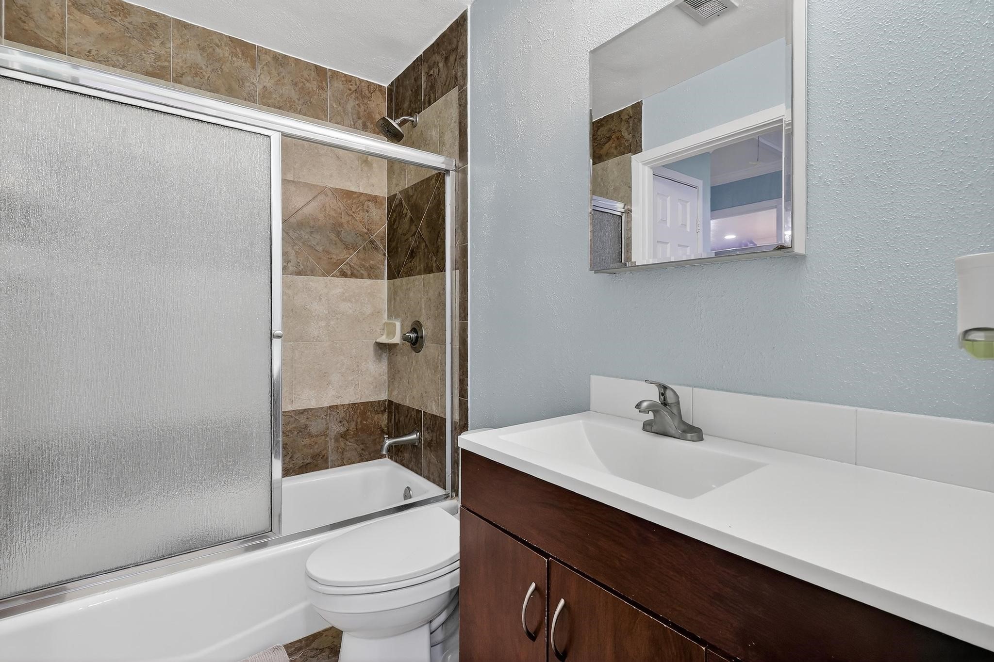 14418 Louetta Road Cypress, TX 77429 - Photo 20 of 39 Updated bathroom with tile-surround tub/shower, sliding glass enclosure, and a modern vanity with solid-surface countertop.
