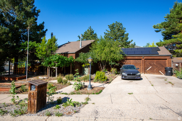 Brown-sided residence featuring a two-car garage with wood-finish doors and rooftop solar panels