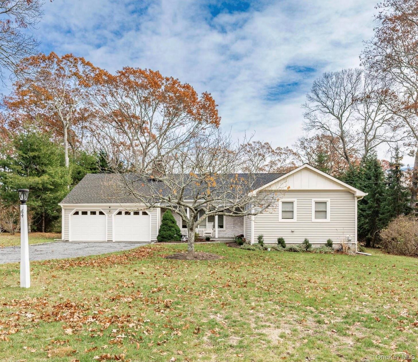 Ranch-style house with board and batten siding, a front yard, asphalt driveway, a garage, and a shingled roof