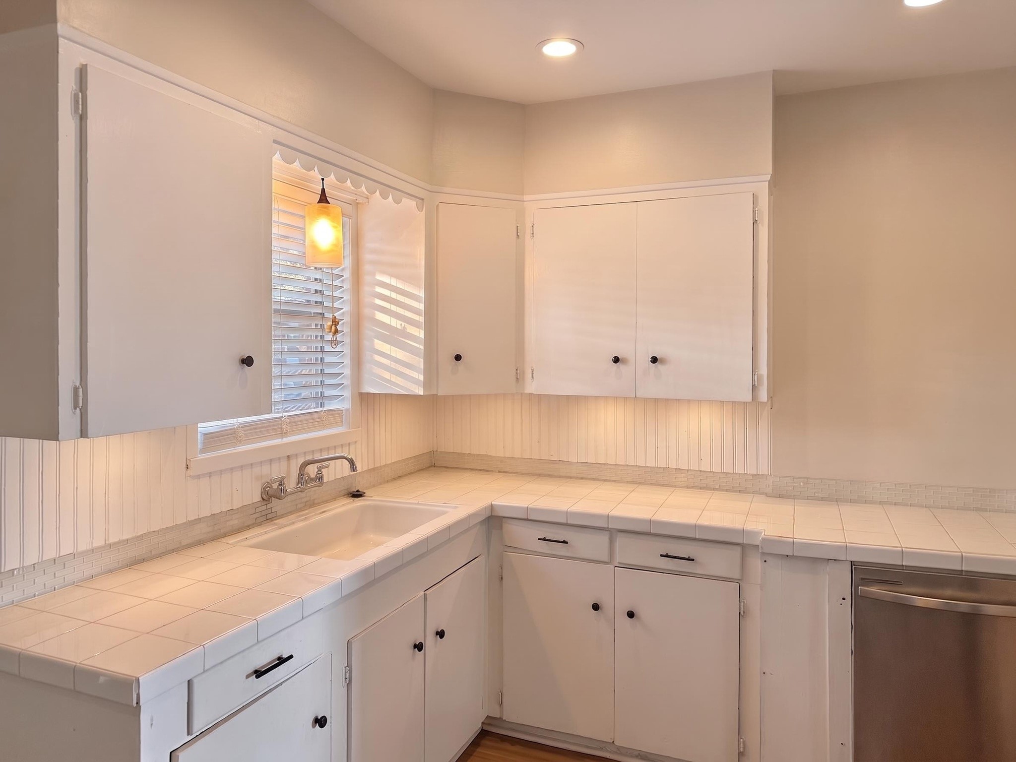 2313 Avenue L Rosenberg, TX 77471 - Photo 10 of 31 Bright kitchen featuring tile countertops, abundant cabinetry, a window above the sink, and plenty of prep space.