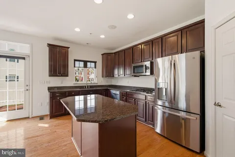 a kitchen with kitchen island a counter top space cabinets and stainless steel appliances