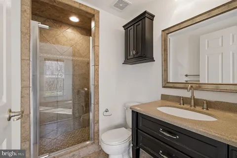 a bathroom with a granite countertop sink a toilet and shower