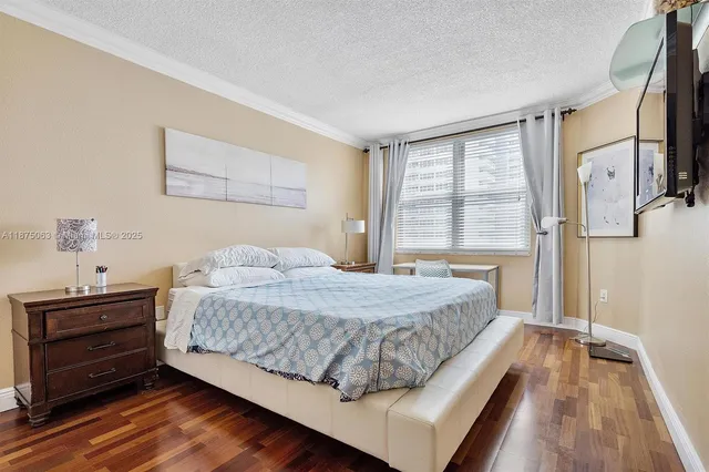 a bedroom with a bed and a dresser with wooden floor