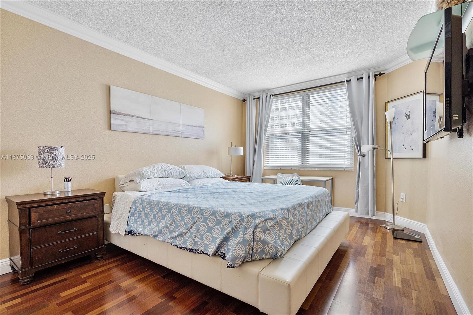 1980 South Ocean Drive, Unit 7N Hallandale Beach, FL 33009 - Photo 9 of 12 a bedroom with a bed and a dresser with wooden floor