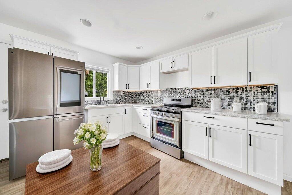 5247 West 3rd Avenue Gary, IN 46406 - Photo 5 of 16 a kitchen with a granite countertop sink stainless steel appliances and white cabinets
