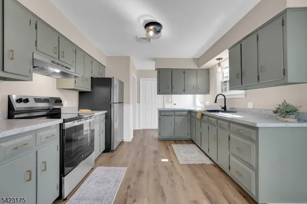 a kitchen with a sink a counter top space stainless steel appliances and cabinets