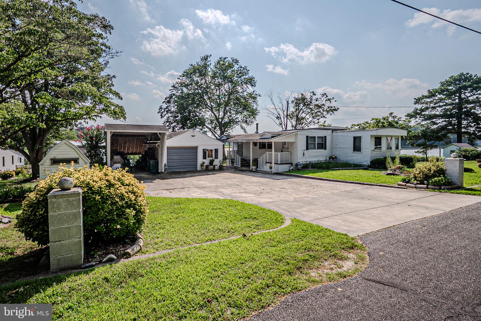 28050 Possum Point Road Millsboro, DE 19966 - Photo 1 of 47 a front view of a house with a garden and trees