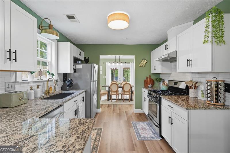 4450 Dorsett Shoals Road Douglasville, GA 30135 - Photo 15 of 36 a kitchen with stainless steel appliances granite countertop a stove a sink and a granite counter tops with white cabinets