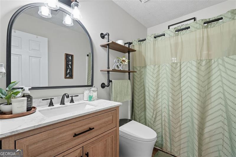 4450 Dorsett Shoals Road Douglasville, GA 30135 - Photo 27 of 36 a bathroom with a granite countertop sink a toilet and a mirror