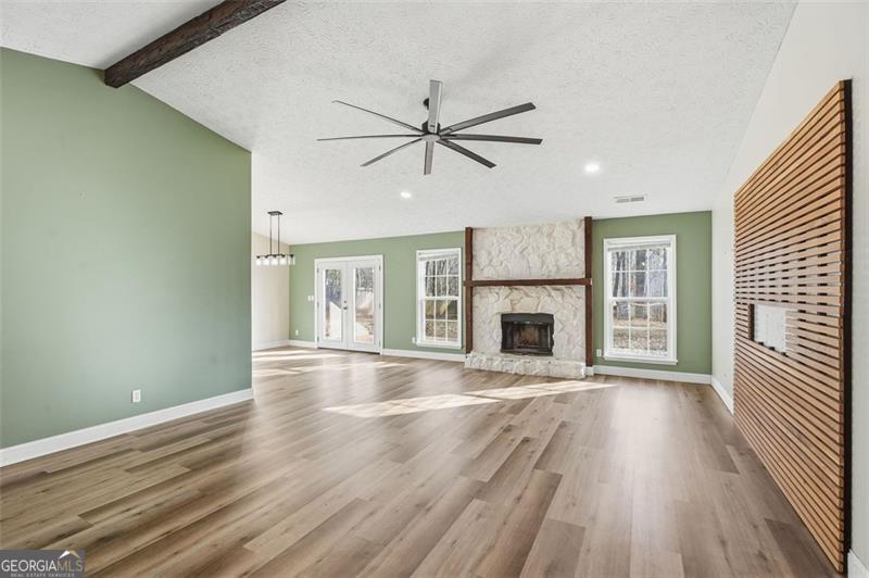 4450 Dorsett Shoals Road Douglasville, GA 30135 - Photo 9 of 36 an empty room with wooden floor a ceiling fan a fireplace and windows