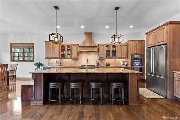 a kitchen with granite countertop a table chairs stainless steel appliances and wooden floor