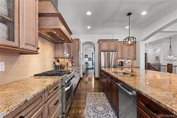 a kitchen with stainless steel appliances granite countertop a lot of counter space and wooden floors