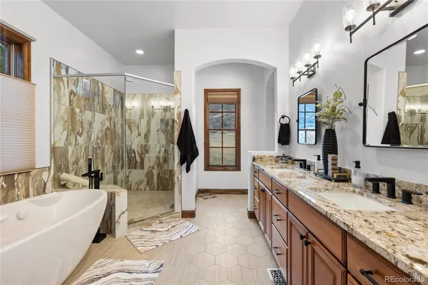 a spacious bathroom with a granite countertop tub sink a mirror a shower and vanity