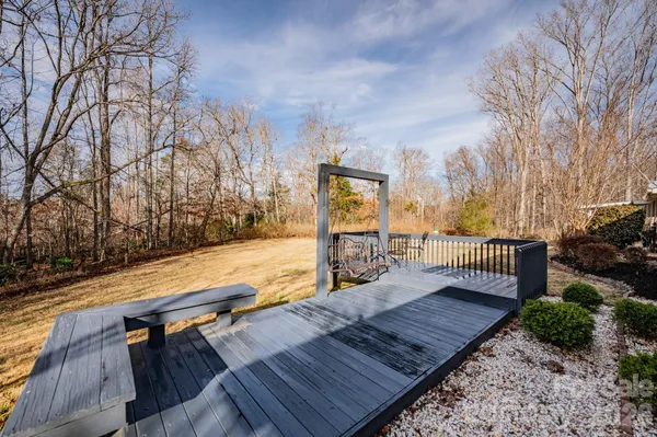 a view of a roof deck with wooden floor and fence with a bench