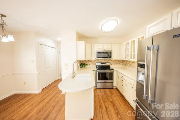 a kitchen with stainless steel appliances a refrigerator a stove a sink and white cabinets