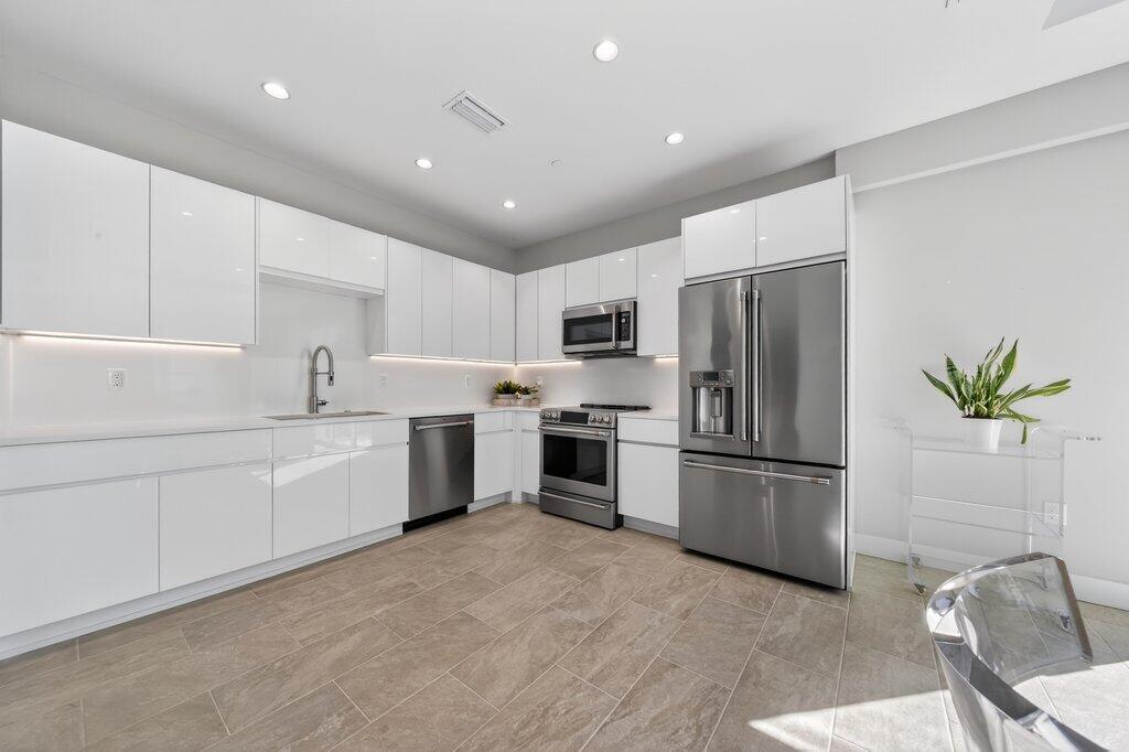 41 Southwest Seminole Street, Unit 209 Stuart, FL 34994 - Photo 12 of 26 a kitchen with white cabinets and stainless steel appliances