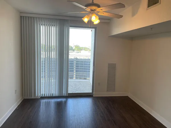 a view of an empty room with wooden floor and a window
