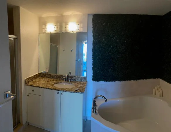 a bathroom with a granite countertop sink a mirror and a bathtub