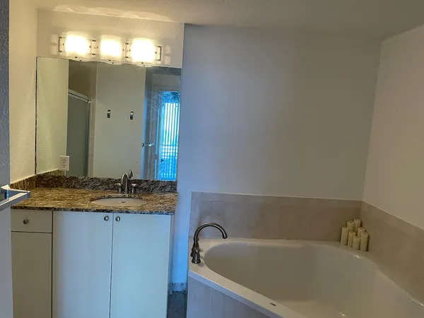 a bathroom with a granite countertop sink and a bathtub