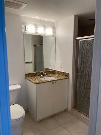 a bathroom with a granite countertop sink toilet and shower