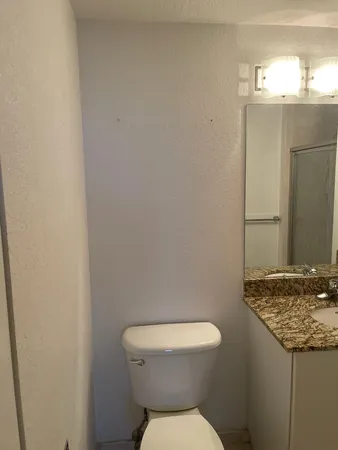 a bathroom with a granite countertop toilet and a sink