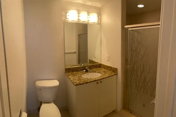 a bathroom with a granite countertop sink and a toilet