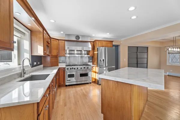 a kitchen with stainless steel appliances granite countertop a refrigerator a stove and a sink with wooden floors