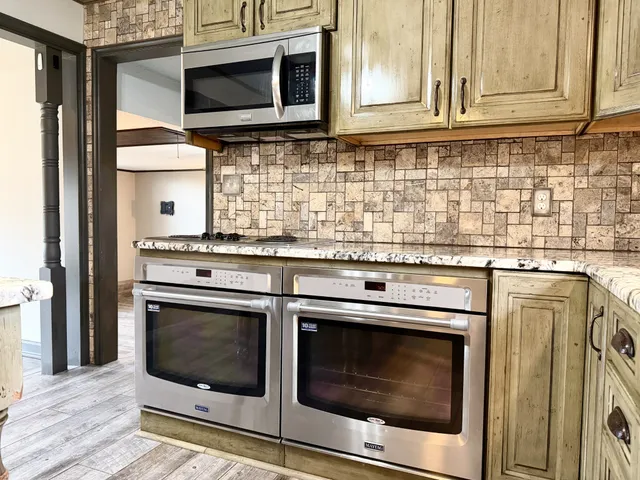 a kitchen with granite countertop cabinets stainless steel appliances and wooden floor