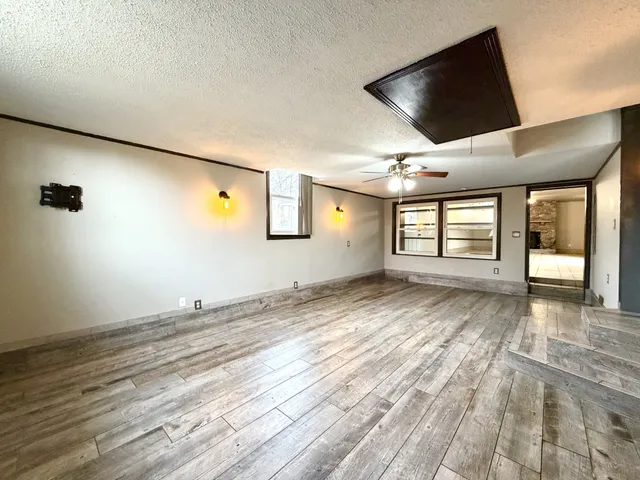 a view of empty room with wooden floor and windows