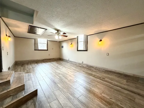a view of empty room with wooden floor and fan
