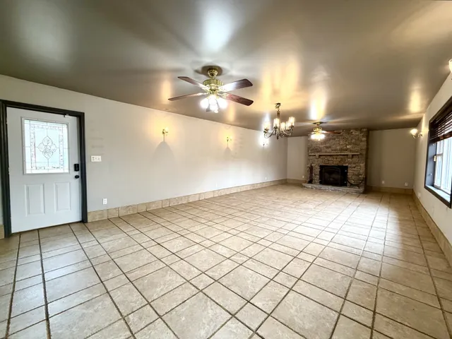 an empty room with kitchen and chandelier fan