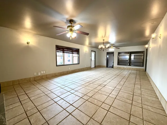 a view of a livingroom with a chandelier fan and windows