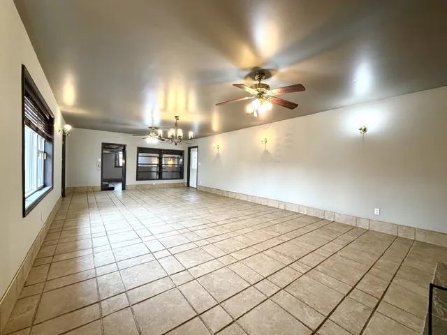 an empty room with kitchen and chandelier fan