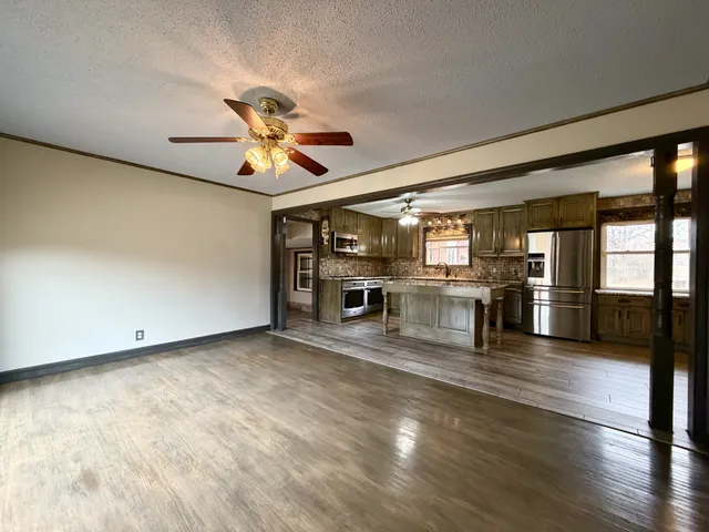 a view of a kitchen with a stove cabinets a ceiling fan and wooden floor