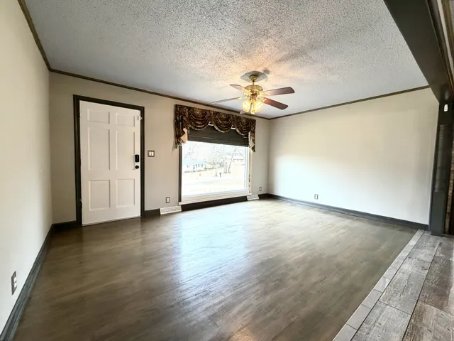 an empty room with chandelier fan and windows