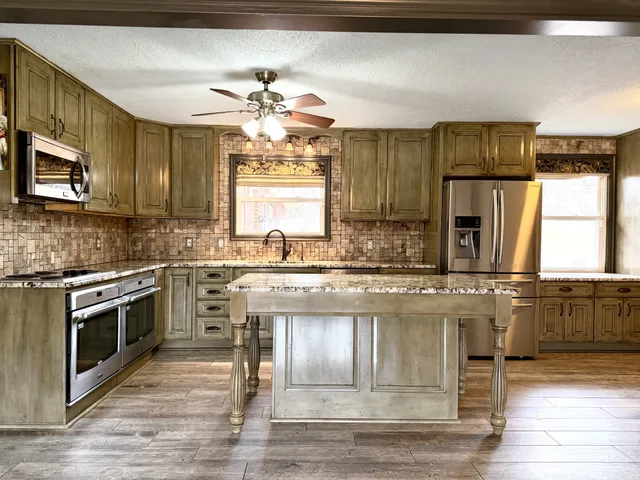 a large kitchen with stainless steel appliances granite countertop a stove and a sink