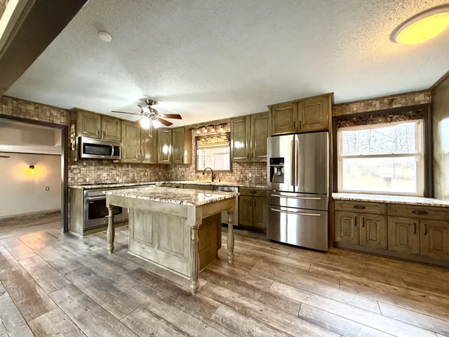 a kitchen with stainless steel appliances granite countertop a stove a sink and a refrigerator