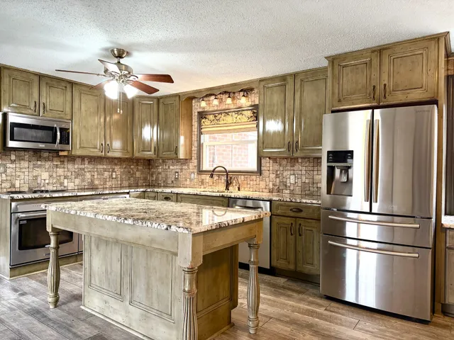 a kitchen with stainless steel appliances granite countertop a refrigerator a stove a sink and a microwave